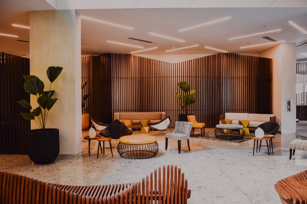 Moderne Hotellobby mit Sofas, Sesseln, Couchtischen, Pflanzen und Holzlattenwänden.